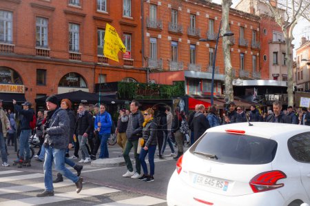 Téléchargez les photos : Toulouse, France -Fév. 2020- Manifestants d'extrême gauche agitant un drapeau portant les caricatures d'Emmanuel Macron et les mots "Stop au racket, nous n'abandonnerons pas, révolution" lors d'une marche contre la réforme des retraites - en image libre de droit