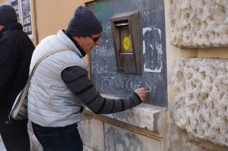 Foto de Toulouse, Francia - Feb. 2020 - Activista de extrema izquierda escribe "La evasión fiscal es un crimen social" en la pared de una sucursal bancaria, en una manifestación del chaleco amarillo (Gilets jaunes) contra la reforma de pensiones de E. Macron - Imagen libre de derechos