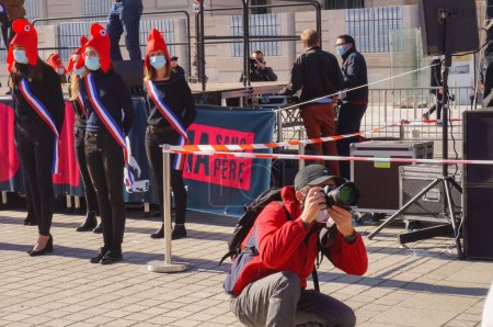 Téléchargez les photos : Paris, France - 10 octobre 2020 - Un photographe de presse professionnel s'agenouille pour prendre des photos lors de la manifestation de Marchons Enfants contre les lois de biéthique, devant les Mariannes de La Manif pour Tous - en image libre de droit