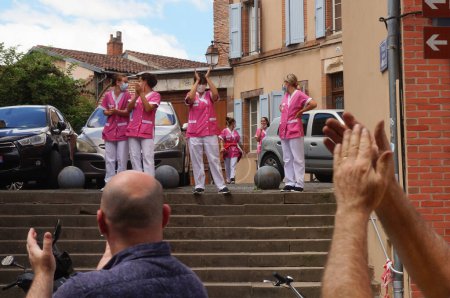 Foto de Albi, Francia - 17 de julio de 2021 - Un grupo de asistentes de enfermería con abrigos rosas aplauden una manifestación contra la vacunación obligatoria y el pase de salud, y son aclamadas por los manifestantes a su vez - Imagen libre de derechos