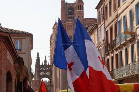 Photo for Albi, France - Aug. 14, 2021 - Tricolor flags of France marked with a Cross of Lorraine, brandished at a demonstration against health passport, at the foot of the gothic Sainte-Ccile's Cathedral - Royalty Free Image