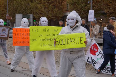 Téléchargez les photos : Albi, France - Novembre 2021 - Des manifestants en blouse blanche d'hôpital, portant des masques de mascarade, descendent dans les rues du centre-ville avec des pancartes, pour exposer les restrictions Covid-19 et les mandats de vaccination - en image libre de droit