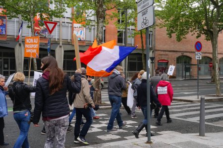 Foto de Albi, Francia - 1 de mayo de 2021 - Marcha contra el bloqueo y las medidas sanitarias represivas organizadas por partidos políticos de derecha y soberanos en el centro de la ciudad; manifestantes portan una bandera y pancartas francesas - Imagen libre de derechos