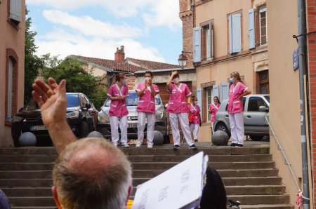 Foto de Albi, Francia - 17 de julio de 2021 - Un grupo de asistentes de enfermería con abrigos rosas aplauden una manifestación contra la vacunación obligatoria y el pase de salud, y son aclamadas por los manifestantes a su vez - Imagen libre de derechos