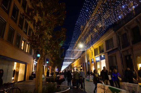 Photo for Toulouse, France - Dec. 2019 - Night perspective of the long Christmas light string that runs the whole length of the crowded Alsace-Lorraine Street, an iconic shopping street in the Pink City - Royalty Free Image