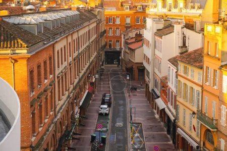 Foto de Toulouse, Francia - Junio 2021 - La antigua calle de Rempart Villeneuve, bordeada de casas adosadas de ladrillo, vistas al amanecer desde lo alto del aparcamiento Victor Hugo, y la cúpula de Galerías Lafayette a lo lejos - Imagen libre de derechos