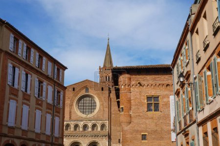 Foto de Perspective of Rue du Taur, a historical street in the centre of Toulouse, in the South of France, lined with old, traditional brick houses and towered by the bell-tower of Notre-Dame du Taur Church - Imagen libre de derechos