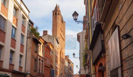 Foto de Perspective of Rue du Taur, a historical street in the centre of Toulouse, in the South of France, lined with old, traditional brick houses and towered by the bell-tower of Notre-Dame du Taur Church - Imagen libre de derechos