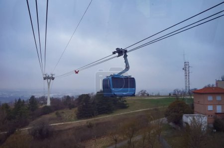 Foto de Toulouse, France - June 2023 - A blue Tlo cable car, hanging on the ropes between two pylons, flies over from Oncopole and goes up towards Rangueil, beyond the River Garonne and Pech-David Hill - Imagen libre de derechos