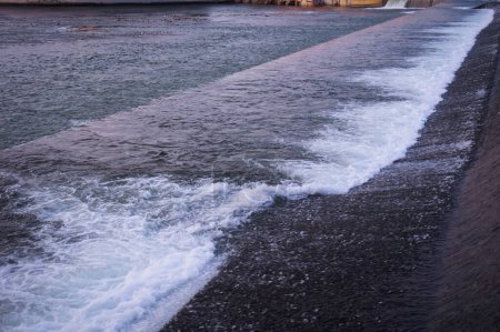 Téléchargez les photos : Wall of water and white foam created by a waterfall on the River Garonne, flowing in Bazacle Causeway, in Toulouse, France, where the strong current is exploited by a hydroelectric dam - en image libre de droit