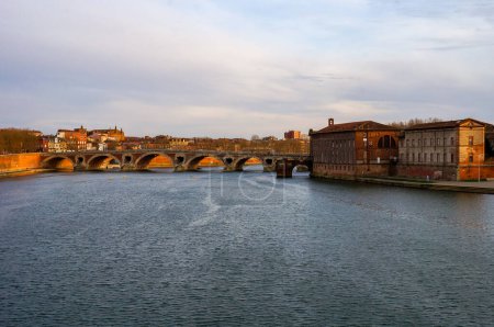 Téléchargez les photos : Coucher de soleil sur la Garonne coulant sous le Pont-Neuf, le plus ancien pont de Toulouse, France ; maisons en briques au bord de la rivière dans les quartiers de Carmes et Saint-Jacques vues depuis le pont voûté de Saint-Pierre - en image libre de droit