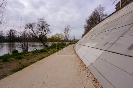Téléchargez les photos : Walkway reserved for cyclists and pedestrians below the concrete anti-flood breakwater of Fer  Cheval by the embankment of the River Garonne in Toulouse, France, deserted amid the 2020-lockdown - en image libre de droit