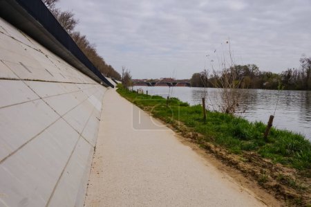 Téléchargez les photos : Walkway reserved for cyclists and pedestrians below the concrete anti-flood breakwater of Fer  Cheval by the embankment of the River Garonne in Toulouse, France, deserted amid the 2020-lockdown - en image libre de droit