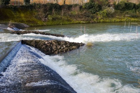 Téléchargez les photos : Water falls, rapids and powerful whirlpools with white foam on the River Garonne in Toulouse, France, seen from the passerelle of Chemin de la Loge between the islands of Grand Ramier and Empalot - en image libre de droit