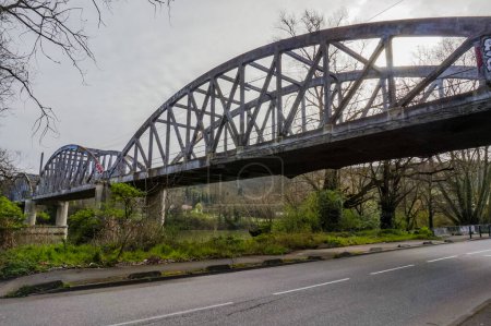 Téléchargez les photos : Toulouse, France - Mars 2020 - Le vieux pont à cordes d'arc abandonné Pont d'Empalot sur la Garonne, vu de la rive ; il présente des poutres latérales en treillis de béton et est dégradé par les graffitis - en image libre de droit