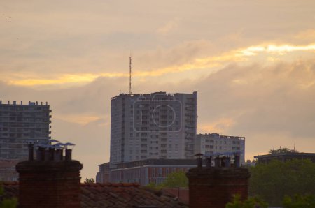 Foto de Toulouse, Francia - Junio 2021 - Edificios de viviendas sociales de gran altura, incluyendo una torre coronada con una antena, en el distrito residencial de Marengo-Jolimont, al amanecer en un cielo amarillo y dorado - Imagen libre de derechos