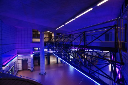 Photo for Toulouse, France - Aug. 2022 - Modern interior of the metro station of Matabiau Train Station, illuminated by night with blue and purple lights ; metal frame of a gangway that overhangs the hall - Royalty Free Image