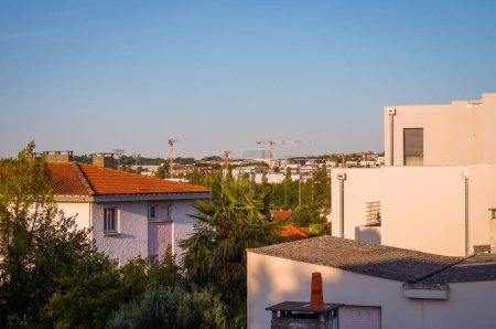 Photo for Morning view from the cosy residential neighborhood of Roseraie, in Toulouse, France, towards the dynamic industrial area of Balma-Gramont, with many tower cranes at the horizon - Royalty Free Image