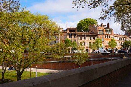 Téléchargez les photos : Toulouse, France - Avril 2019 - Espaces verts sur la place Port de la Daurade, au bord de la Garonne, bordé par des maisons de ville typiques du sud de la brique, au bout de la rue Gambetta dans le quartier du Capitole - en image libre de droit