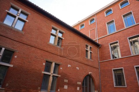 Photo for Toulouse, France - Nov. 2019 - Brick building of Lycee Pierre de Fermat, including an older part of Bernuy Castle having Renaissance muntin windows and vaulted door ; bicycle parking in courtyard - Royalty Free Image