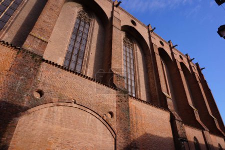 Foto de Cara sur de la iglesia construida en ladrillo del Convento Jacobino, en Toulouse, Francia, un monumento medieval gótico-meridional, con grandes vidrieras, imponentes contrafuertes y gárgolas a lo largo del techo - Imagen libre de derechos