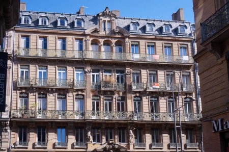 Foto de Toulouse, Francia - Ene. 2020- Fachada típica de un elegante edificio de la ciudad de Hausmann, con techo de mansarda, balcones y tiendas de lujo en la planta baja, en la calle Alsacia-Lorena, frente a la plaza De Gaulle - Imagen libre de derechos