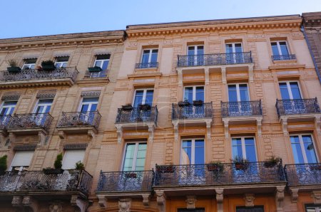 Foto de Toulouse, Francia - Ene. 2020- Fachada típica de un elegante edificio de la ciudad de Hausmann, con techo de mansarda, balcones y tiendas de lujo en la planta baja, en la calle Alsacia-Lorena, frente a la plaza De Gaulle - Imagen libre de derechos