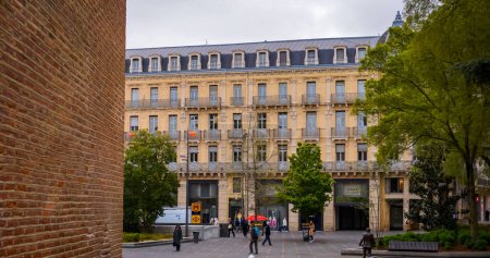 Photo for Toulouse, France -Jan. 2020- Typical facade of an elegant Hausmann town building, with mansard roof, balconies and upscale shops on the ground floor, in Alsace-Lorraine Street, facing De Gaulle Square - Royalty Free Image