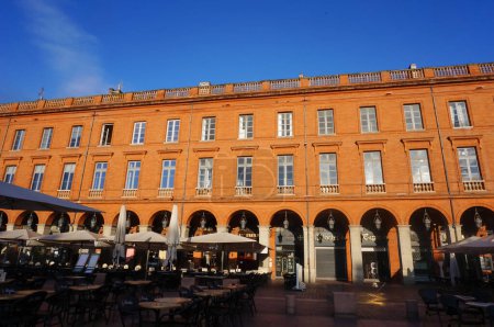 Foto de Toulouse, Francia - Ene. 2020 - Curvas y antiguas casas típicas del sur, construidas en ladrillo rosa y naranja en Place Wilson, una icónica plaza circular en el histórico barrio peatonal de Capitole - Imagen libre de derechos