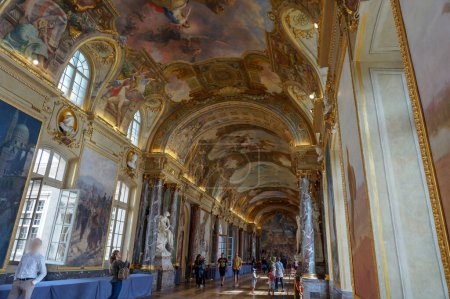 Photo for Toulouse, France - September 2018 - The gallery and wedding hall of the city hall ("Salle des Illustres du Capitole") decorated by frescos on the vault ceiling, paintings and sculptures, and visitors - Royalty Free Image