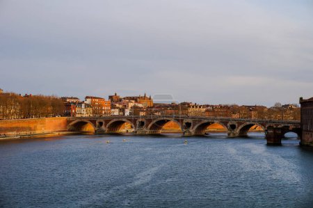 Foto de Las olas y el agua verde del río Garona en Toulouse, Francia, que fluyen bajo los arcos del puente de ladrillo Pont du Halage de Tounis cerca de la compuerta de Saint-Michel, en un hermoso día soleado - Imagen libre de derechos