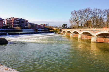 Foto de Las olas y el agua verde del río Garona en Toulouse, Francia, que fluyen bajo los arcos del puente de ladrillo Pont du Halage de Tounis cerca de la compuerta de Saint-Michel, en un hermoso día soleado - Imagen libre de derechos