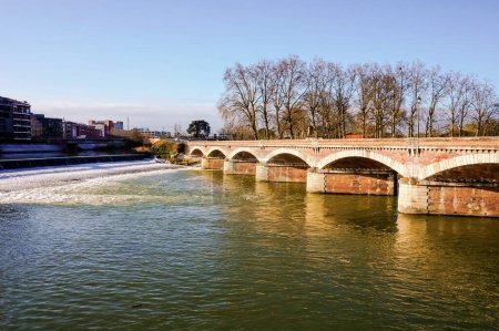 Téléchargez les photos : Les vagues et les eaux vertes de la Garonne à Toulouse, en France, coulent sous les voûtes du pont en brique Pont du Halage de Tounis près de l'écluse de Saint-Michel, par une belle journée ensoleillée - en image libre de droit
