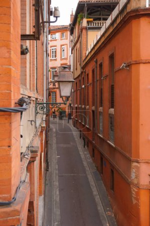 Un paisaje típico en el centro histórico de Toulouse, Francia: la estrecha calle de "Descente de la Halle-aux-Poissons" (Descenso al mercado de pescado), bordeada de edificios de ladrillo antiguos y tradicionales