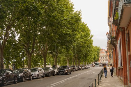 Photo for Toulouse, France - July 2020 - Perspective of the tree-lined Street of Quai de Tounis, which goes along the River Garonne, bordered by the typical brick houses of the historic neighborhood of Carmes - Royalty Free Image