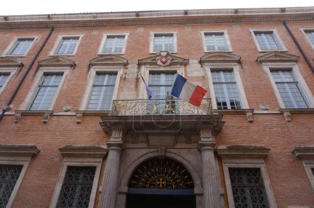 Photo for Toulouse, France - April 2019 - Front monumental facade of the Renaissance and baroque-style Hotel of Knights of Saint-Jean or Grand Priory of Malta, with a flying French flag on the balcony - Royalty Free Image