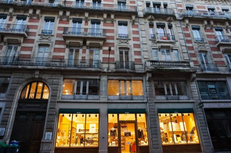 Foto de Toulouse, Francia - dic. 2019 - Lujosa casa antigua de ladrillo, con balaustradas de balcón y puerta abovedada, con el escaparate iluminado de la tienda de lujo de la marca de moda francesa Bexley - Imagen libre de derechos