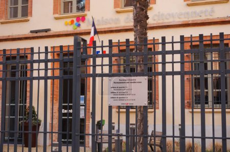 Foto de Toulouse, Francia - Feb. 2020 - Valla y cartelera informativa del anexo del ayuntamiento ("Casa de la Ciudadanía") del distrito de Toulouse-Carmes, en la calle Rue Paul Meriel, con bandera francesa - Imagen libre de derechos