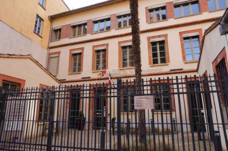Foto de Toulouse, Francia - Feb. 2020 - Edificio del anexo del ayuntamiento ("Casa de la Ciudadanía") del distrito de Toulouse-Carmes, en la calle Rue Paul Meriel, con una fachada de ladrillo y una puerta de hierro fundido - Imagen libre de derechos