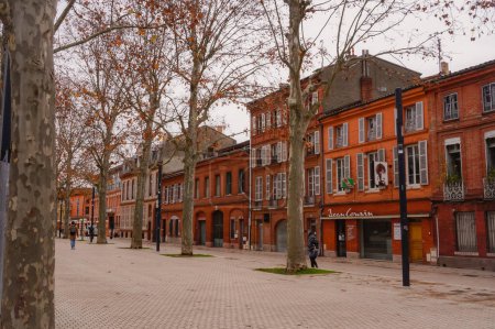 Photo for Toulouse, France - Dec. 2020 - Traditional old townhouses built in red brick by the tree-lined of the pedestrianized promenade of Allees Jean-Jaures, a street in the neighborhoods of Saint-Michel - Royalty Free Image