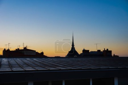 Foto de Hermosa salida del sol al amanecer en un cielo amarillo, rosa y azul con las siluetas de techos de edificios antiguos salpicados de antenas de televisión en el distrito de Carmes, en Toulouse, Francia, incluyendo una cúpula puntiaguda - Imagen libre de derechos