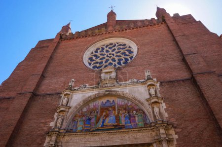 Photo for Rose window and painted tympanum on the brick facade of the church of Notre-Dame de la Dalbade, in the historic quarter of Carmes in Toulouse, Southern France, picturing the crowning of the Virgen - Royalty Free Image