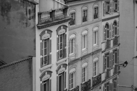 Foto de Toulouse, France - Jan. 2021 - Old brick townhouses, with typical louvered shutters and shops on the ground floor, by Rue des Filatiers Street, in the historic neighborhood of Carmes (black and white) - Imagen libre de derechos