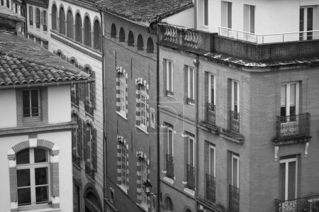 Foto de Toulouse, France - Jan. 2021 - Old brick townhouses, with typical louvered shutters and shops on the ground floor, by Rue des Filatiers Street, in the historic neighborhood of Carmes (black and white) - Imagen libre de derechos