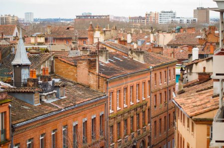 Téléchargez les photos : Toulouse, France - Jan. 2021 - Elevated view in long focal length on the old, typical brick town buildings of Rue des Prtres Street, in Les Carmes, a historic neighborhood in the center of the city - en image libre de droit