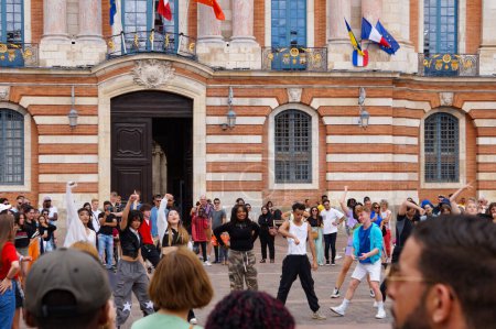 Téléchargez les photos : Toulouse, France - 1er juillet 2023 - Une foule éclair avec de jeunes danseurs de rue se produisant sur la place du Capitole, la place principale de la ville, au pied de l'hôtel de ville, et des spectateurs formant le public - en image libre de droit