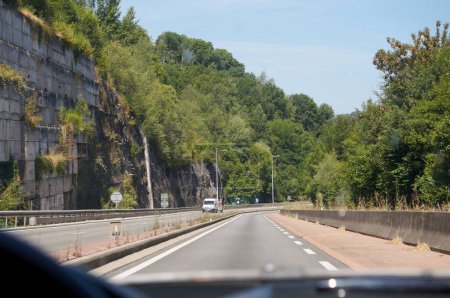 Foto de Rodez, Francia - 14 de agosto de 2023 - National Road RN88, bordeado por una pared de roca en un lado y bordeado de bosques; al cruzar Rodez, sirve como una carretera de circunvalación para evitar la ciudad, yendo hacia el norte. - Imagen libre de derechos