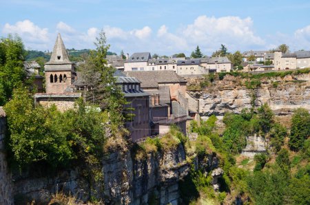 Téléchargez les photos : L'église romane Sainte-Fauste du XIIe siècle, à Bozouls ; le village médiéval et historique est construit sur les falaises rocheuses du Canyon de Bozouls, dans la vallée du Lot, dans le sud de la France - en image libre de droit