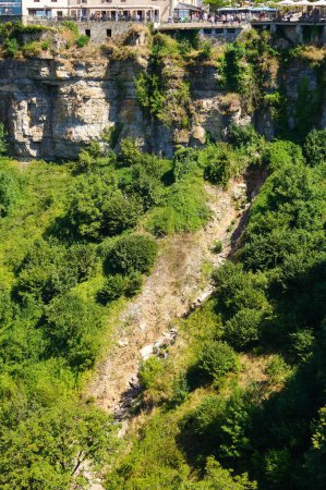 Téléchargez les photos : Rochers (glissement rocheux) composés de galets de pierre calcaire tombés sur la pente des parois rocheuses du canyon de Bozouls, dans la vallée du Lot, en France ; le village est construit sur le bord de la falaise - en image libre de droit