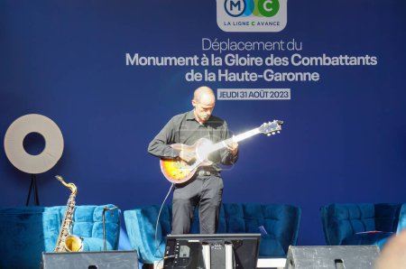 Photo for Toulouse, France - Aug. 31, 2023 - Structure relocation of Franois Verdier War Memorial: a musican is on stage to entertain the public during the pre show ahead of the event, playing the guitar - Royalty Free Image